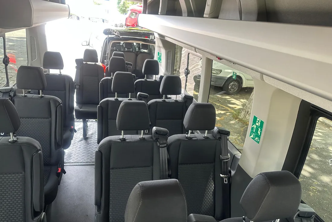Passenger seats and overhead luggage racks inside the Ford Transit minibus