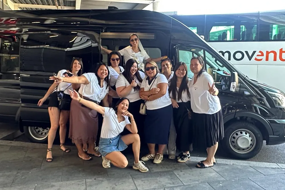 Group of passengers posing next to a black BCN Minibus van at the airport